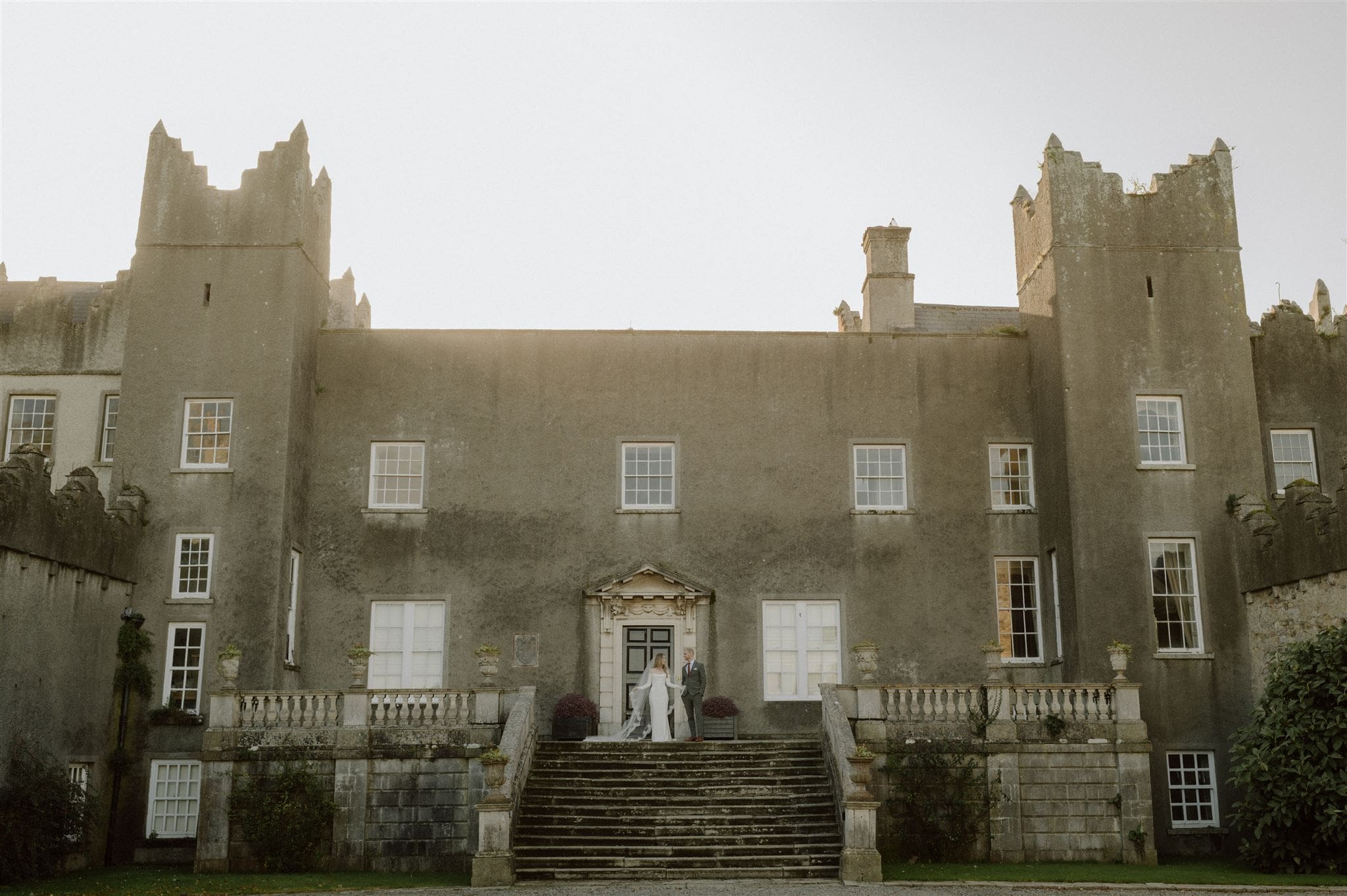 Bride and groom stand on the steps of Howth Castle in Ireland after their elopement.