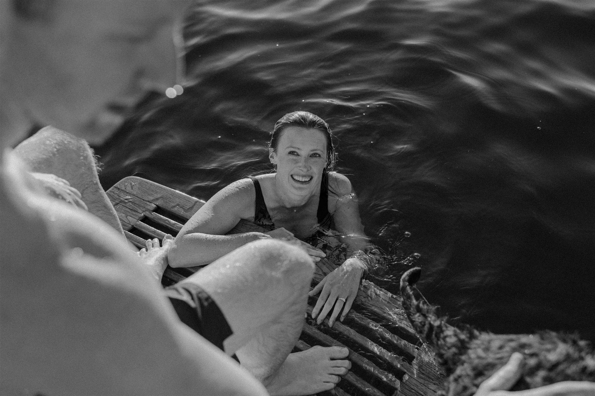 A couple swims in the water by their boat during their engagement session in Muskoka
