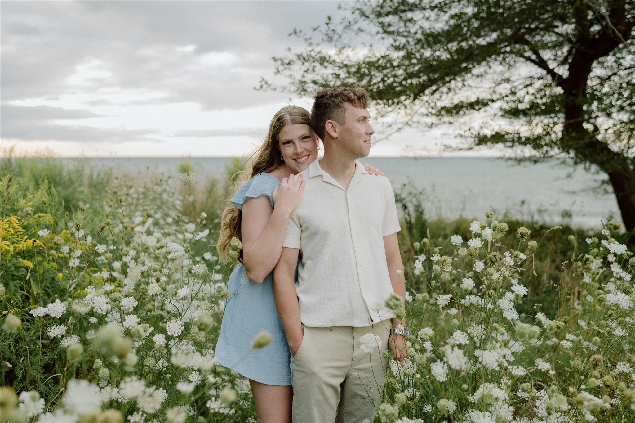 A couple embraces in a wildflower field along a beach in Niagara, Ontario.