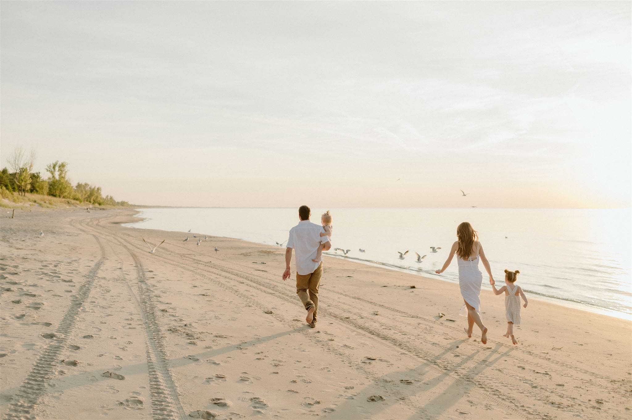 A family walks down the beach at sunset at Pinery Provincial Park during a family session.