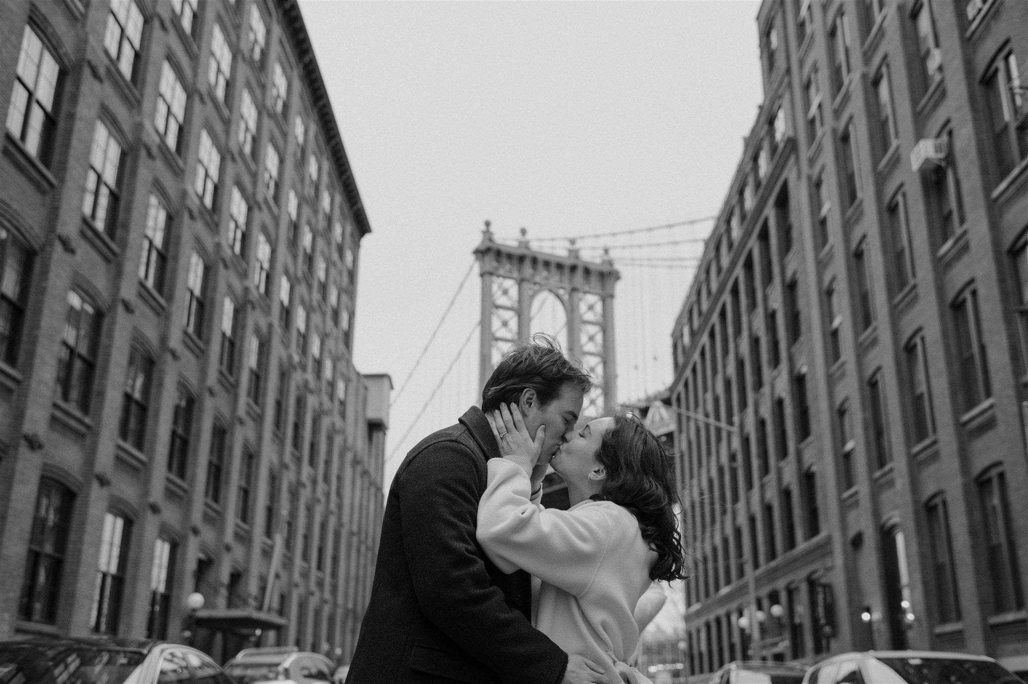 Couple embrace in front of the Manhattan Bridge during their engagement session.